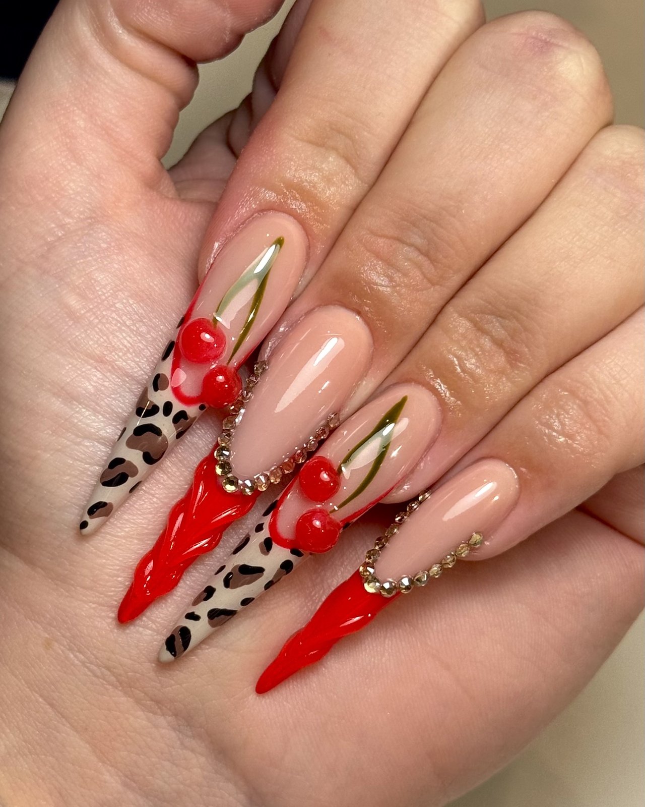 Lange nagels met rood, luipaardprint, goud en steentjes