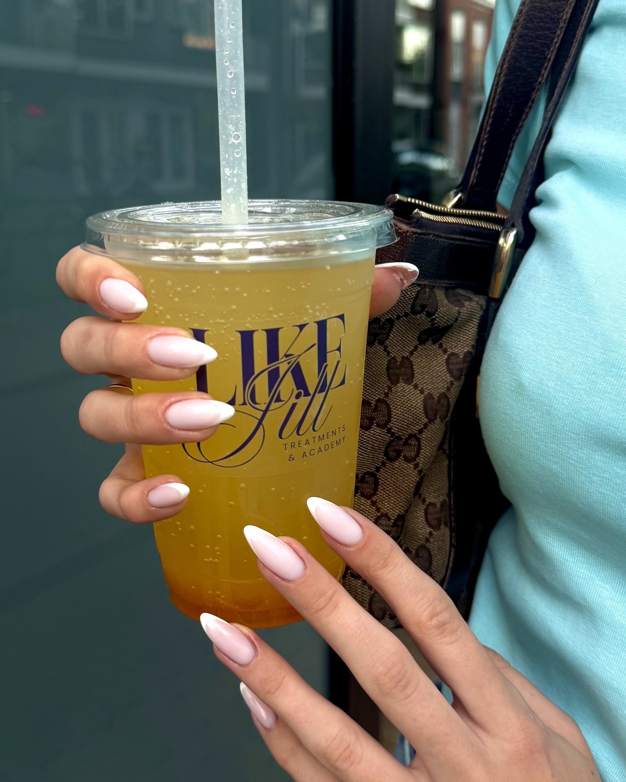 Hand met lichtroze nagels houdt een drinkbeker met het Like Jill logo vast